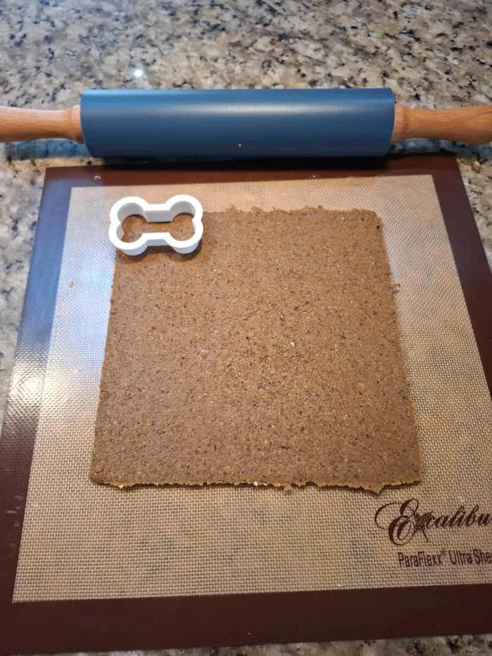 Dog biscuit dough rolled out flat next to the printed frame and cutter, ready to be cut into biscuits